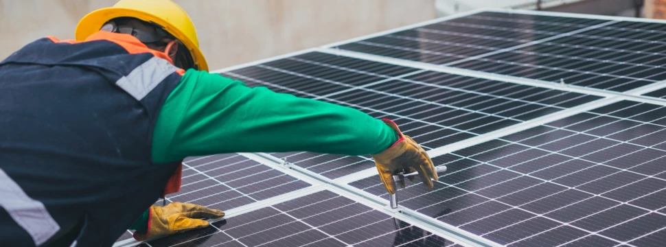 Ein Arbeiter befestigt eine Photovoltaik-Anlage