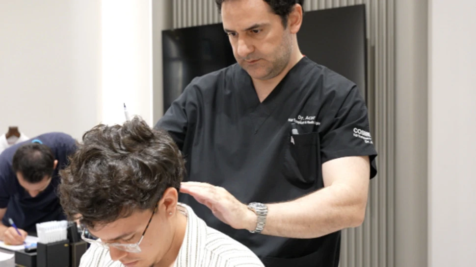 Mann sitzt auf einem Friseurstuhl und lässt von einem anderen beraten