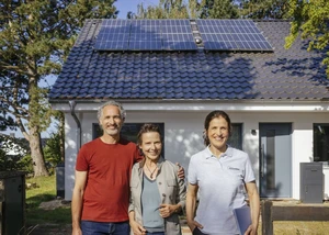 zwei Frauen und ein Mann stehen vor einem weißen Haus