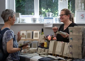 zwei Frauen an einem Ausstellungsstand mit Drucksachen