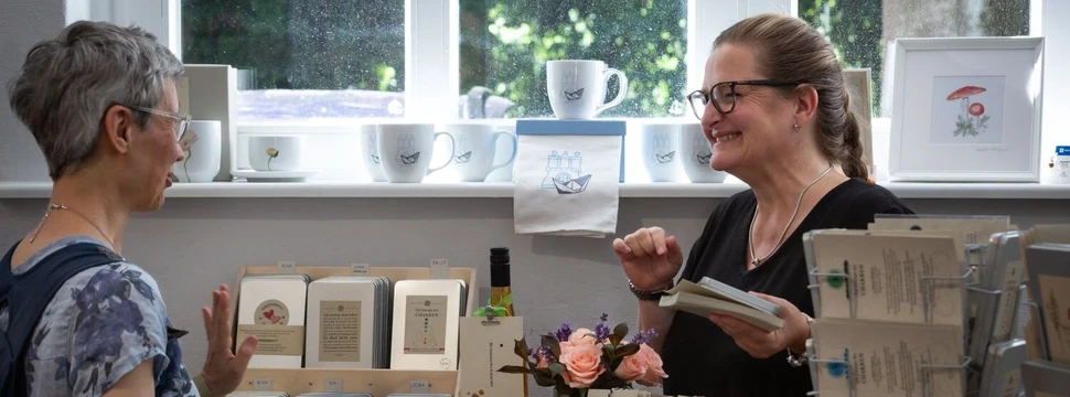 zwei Frauen an einem Ausstellungsstand mit Drucksachen