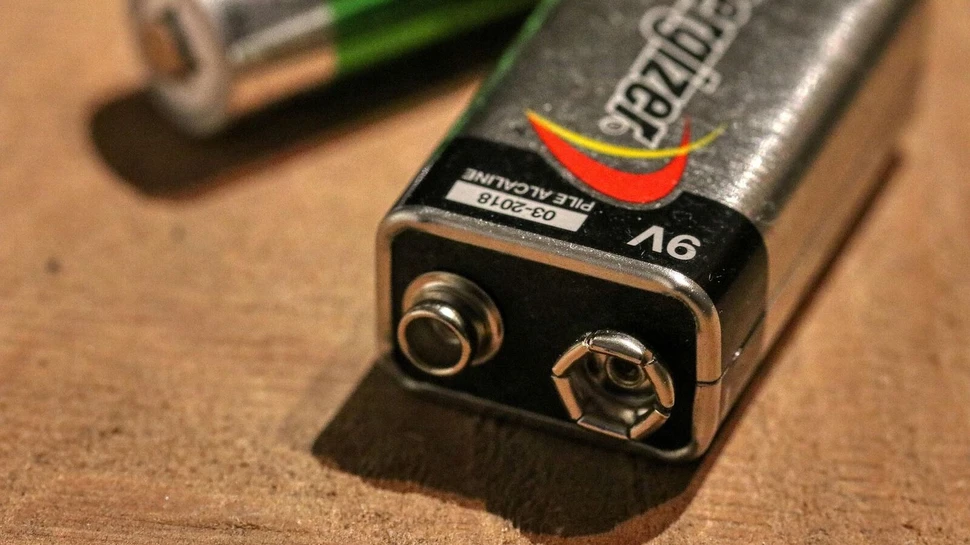 zwei Batterien liegen auf braunem Untergrund