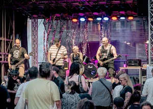 Ein Band ist auf der Bühne. Vor der Bühne sind einige Mensche