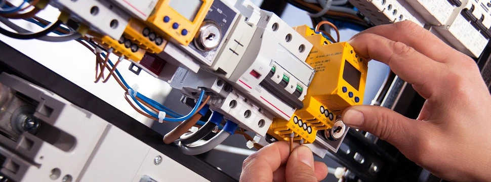 Hände, die ein Kabel in einem elektrischen Schaltkasten befestigen