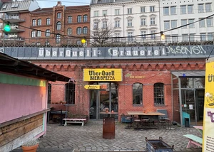 Blick auf ein Backsteingebäude mit einem großen gelben Schild vom ÜberQuell