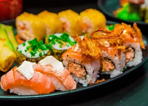 verschiedene Sorten Sushi und Sashimi auf einem schwarzen Teller