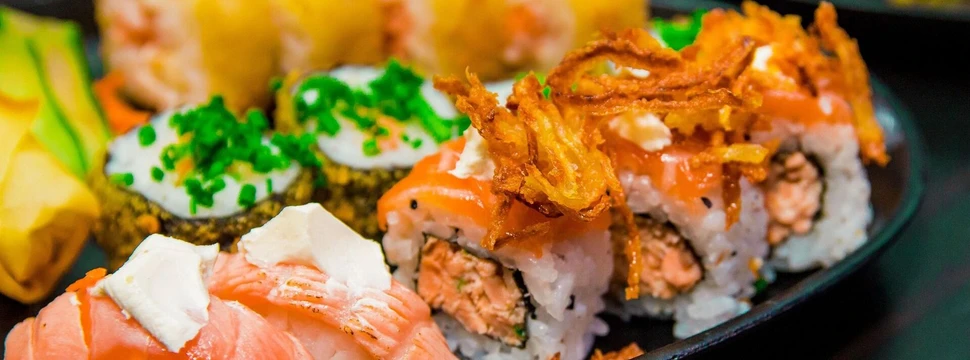 verschiedene Sorten Sushi und Sashimi auf einem schwarzen Teller
