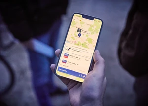 Eine Hand hält ein Smartphone, auf dem das Mobilitätsangebot HUUS geöffnet ist