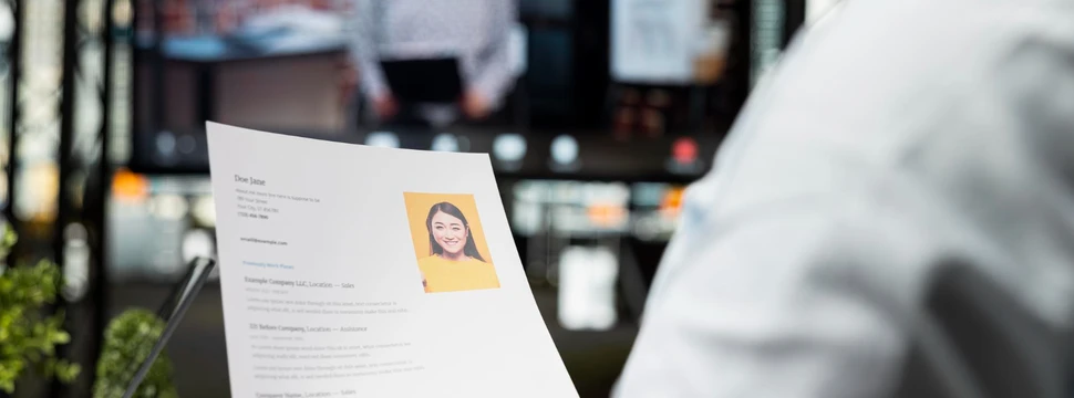 Eine Person mit einem Blatt Papier in der Hand, die an einem Tisch sitzt