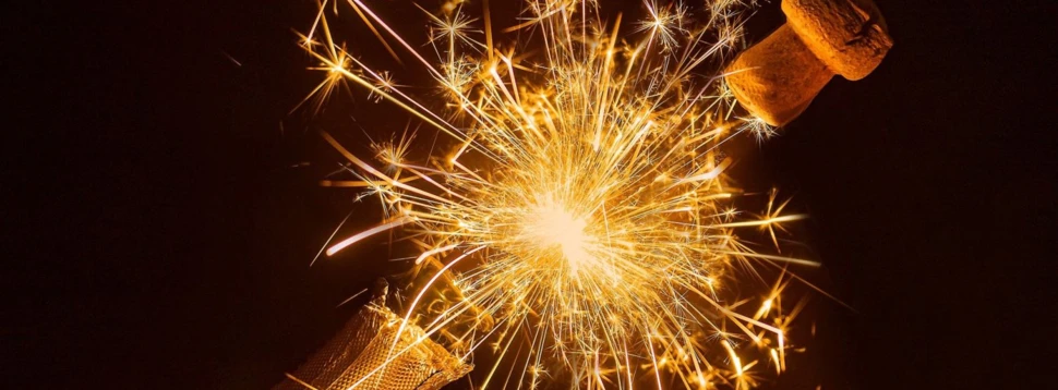Sektflasche mit explodierendem Korken und goldenem Funkenregen zu Silvester in Hamburg