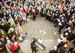Viele Zuschauende stehen bei Liedstadt Hamburg im Kreis um einen Musiker.