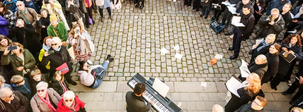 Viele Zuschauende stehen bei Liedstadt Hamburg im Kreis um einen Musiker.